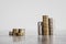 Stacks of different coins divided between a small and a big group on white background, good vs bad investements or before and