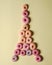 Stacks of donuts of various colors with a topping of powdered sugar form a tower.