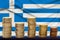 Stacks of euro currency coins against the background of the silk flag of Greece, the concept of financial growth, the dynamics of