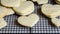 Stacks of heart shaped sugar cookies on a black wire cooling rack, granite kitchen counter