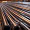 Stacks of metal pipes, construction components for industry, in storage in warehouse