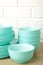 Stacks of mint ceramic dishware on light background