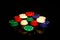 Stacks of poker chips with a green chip in front isolated on black with reflections