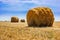 Stacks of straw on sloping wheat field