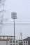 Stadium floodlight with metal pole, lighting mast, tower with floodlights in the sports stadium against the white sky