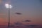 Stadium night lights over football field during sunset with cumulous clouds