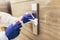 Staff using disinfectant from the bottle spraying an elevator push button control panel.