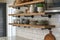 Stage shelves in a kitchen featuring minimalist black metal pipe brackets that are one rod and feature a circular base on the wall