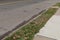 Stained asphalt street with grass strip and concrete sidewalk