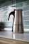 Stainless geyser coffee maker on a background of blue tiles