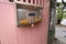 Stainless mailbox with texture was locked by a pink 3-digit combination padlock that was hanging on a wooden door