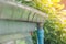 Stainless rain gutter on roof of wooden house with sunlight background.