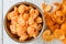 Stainless-steel bowl filled with peeled clementine orange sections, and peels on a white wood background