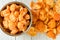 Stainless-steel bowl filled with peeled clementine orange sections, and peels on a white wood background