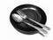 Stainless steel cutlery set on a plate black ceramic isolated on white background