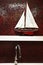 Stainless steel faucet with sailboat model on shelf with red pat