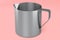 Stainless steel milk frothing pitcher cup with handle on pink background.