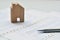 Stainless steel pen tip on documents pile with wooden blurred model house is background.