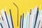 Stainless steel reusable drinking straw with many multicolored plastic straws on yellow background