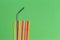 Stainless steel reusable drinking straw with plastic straws on green background
