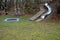 Stainless steel slide on the playground with concrete hills and rocks and wooden staircase. Large glossy tube for sliding children