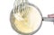 Stainless steel whisk with creamy cream cheese and metal pot