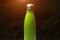 Stainless thermo bottle for water, tea and coffe. Dark grass background with sunlight effect. Thermos green color.