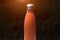 Stainless thermo bottle for water, tea and coffe. Dark grass background with sunlight effect. Thermos orange color.