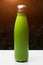 Stainless thermo bottle for water, tea and coffe, on white table. Dark grass background with sunlight effect. Thermos green color.