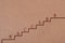 A staircase is drawn on a brown texture background. Each step has a letter on it.