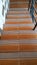 Stairs descending a house with orange stripes with black handles