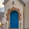 Stairs leading to the vibrant blue arched door at the entrance of a home