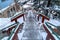 Stairway and road on snow covered hill amid houses and coniferous trees