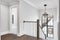 The stairwell and hallway in a luxury home with a modern light hanging above the stairs.