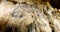 Stalactite and stalagmite formations on the rocky walls of a large underground cave