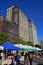 Stalls, vendors & crowd at Farmers Market at Union Square park with tall buildings in the background, Manhattan, New York City