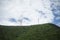 Stanchion of Telecommunication mast TV antennas wireless technology on a hilltop of green mountain, blue sky and cloud