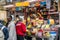 Stand with fresh cheese specialities, dairy products and sausages at an Italian street market. Many customers in front of the mark