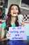 Stand out. an attractive young woman holding up a sign while enjoying a milkshake in a retro diner.