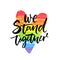 We stand together. Inspirational LGBT slogan han dwritten on rainbow flag heart.