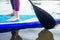 Stand up paddle boarding on a quiet sea lake , close-up of legs and water splash