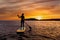 Stand up paddle boarding on a quiet sea with warm summer sunset colors.