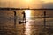 Stand-up paddler silhouettes at sunset