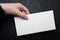 Standard white blank of mail envelope in hand on a black background. Mock up