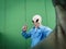 Standing alien mask face taking selfie picture against green background wall. Copy space for comic funny advertising. Ufo