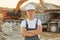 Standing with arms crossed. Worker in professional uniform is on the borrow pit at daytime