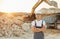 Standing with arms crossed. Worker in professional uniform is on the borrow pit at daytime