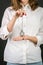 Standing blonde girl in a white shirt with red lacquer, blue jeans, holding a vintage silver watch on a chain. Isolated on black b