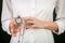 Standing blonde girl in a white shirt with red lacquer, holding a vintage silver watch on a chain. Isolated on black b