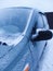 Standing car in a snow storm. Gray car covered with snow and ice close-up. Snowy weather in winter